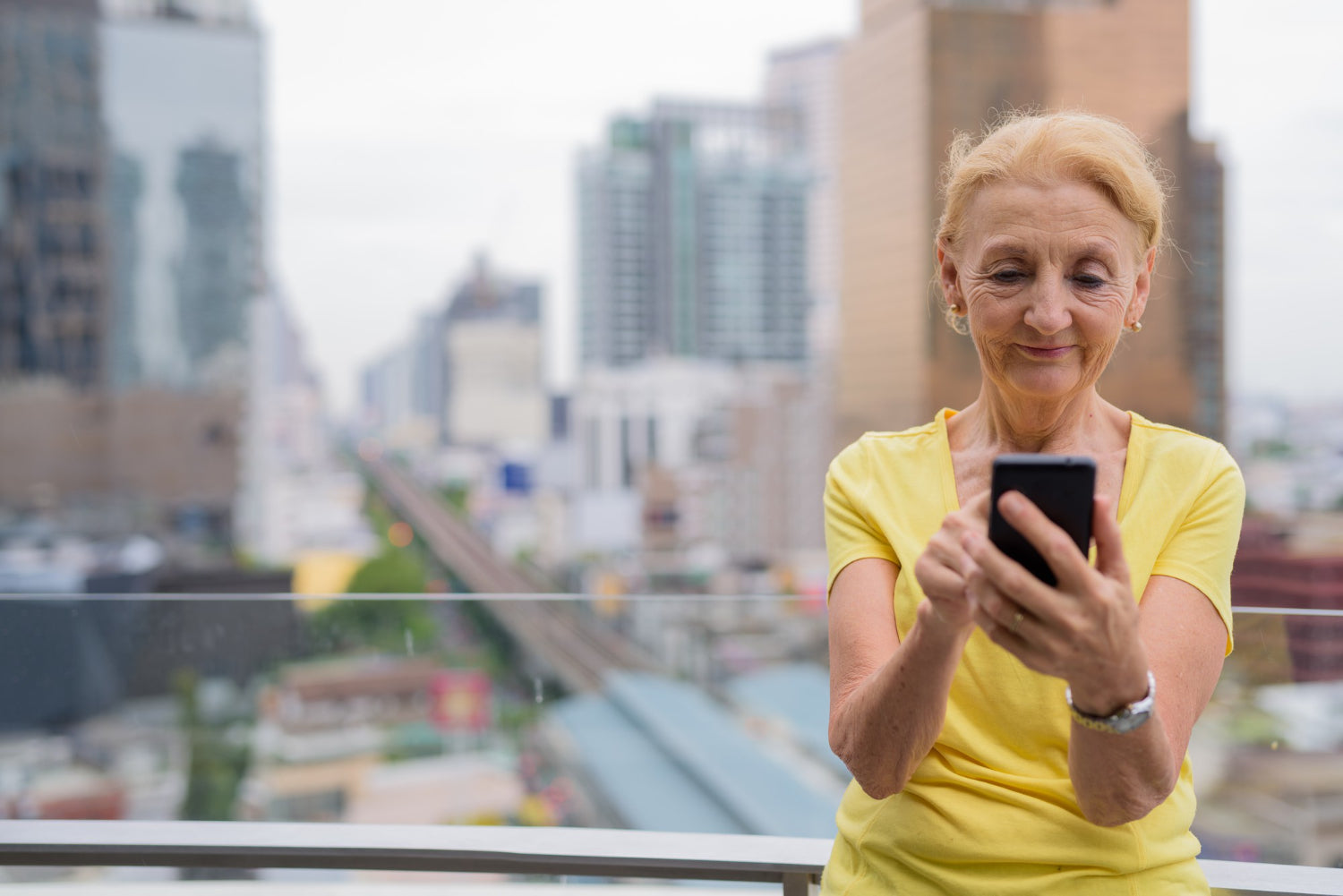 Woman using a smartphone with a cityscape in the background